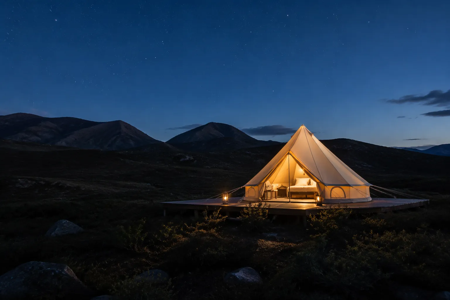 Canvas bell tent on a wooden platform at twilight beneath a darkening mountain sky