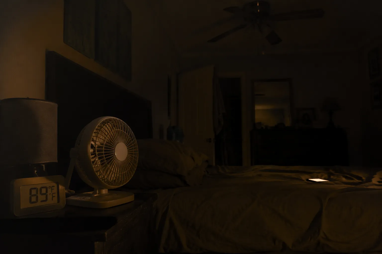 Dark bedroom during a power outage heat wave with a thermometer reading 89°F