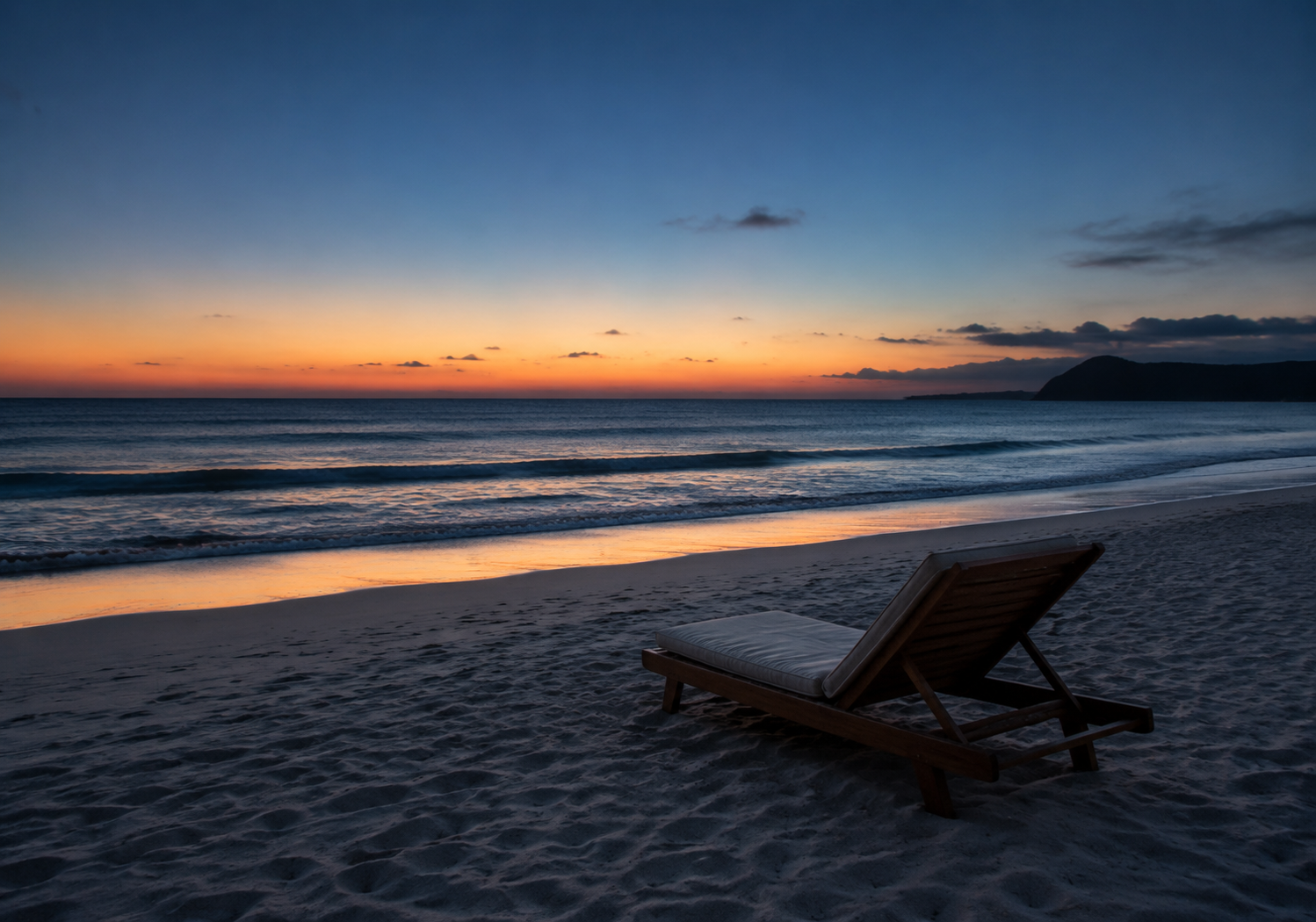 Empty twilight beach with gentle waves and a single lounge chair near the water