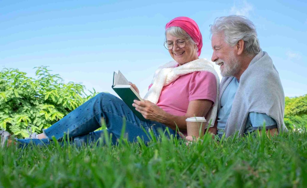 Two older adults sitting outdoors on a sunlit park bench in the morning