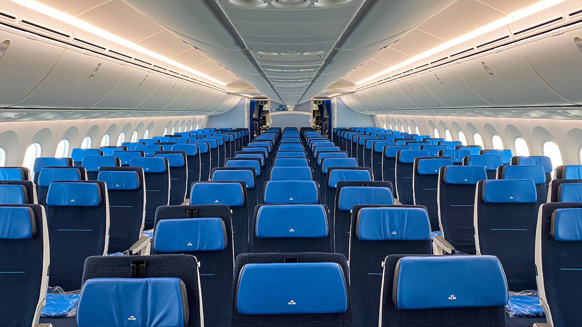 Boeing 787 Dreamliner cabin with blue LED lighting, large overhead bins, and oversized windows