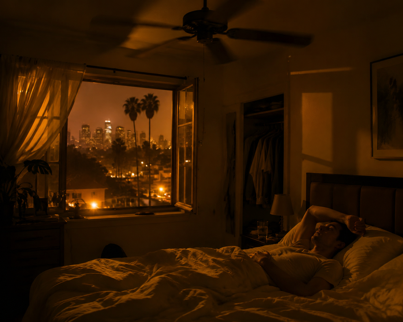 A dimly lit Los Angeles bedroom at night during a heat wave with a ceiling fan spinning over rumpled white sheets and a person lying awake by an open window.