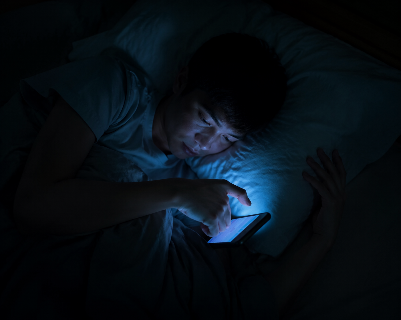 Person lying in a dark bedroom using a smartphone one-handed with the wrist bent downward