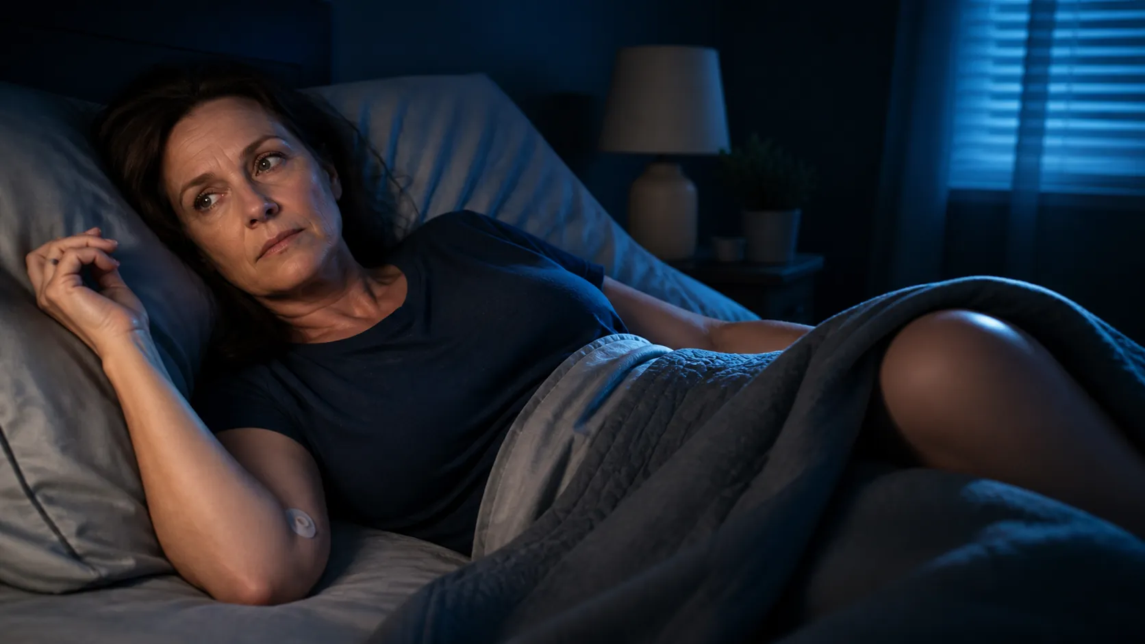 Woman lying awake after a recent blood donation with restless legs under the covers