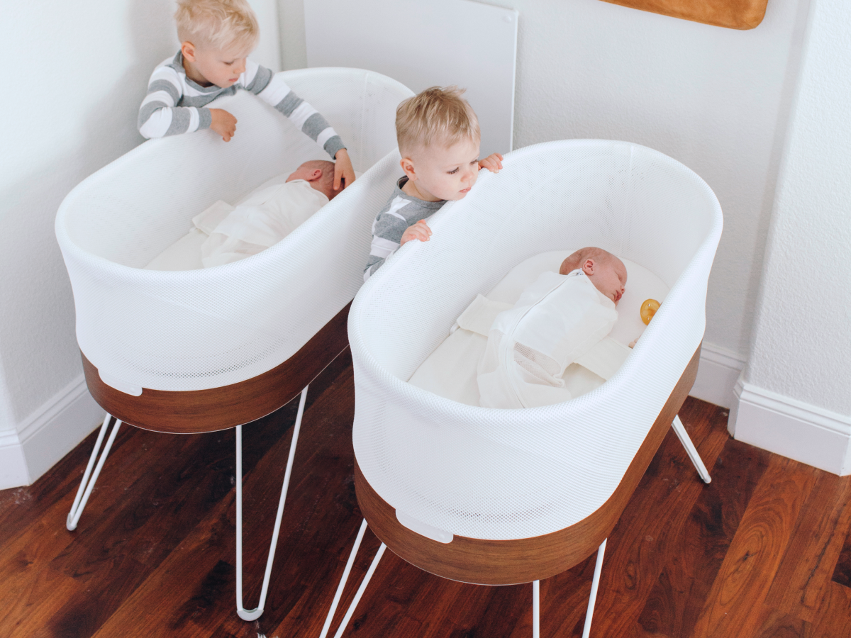 The Snoo Smart Sleeper bassinet in a white nursery setting with a visible sleep sack